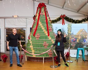 Coworkers in front of can-donation Christmas tree 