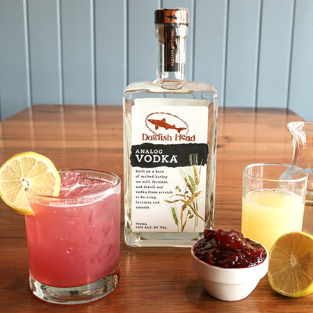 Analog Vodka bottle surrounded by cocktail glass and cocktail ingredients