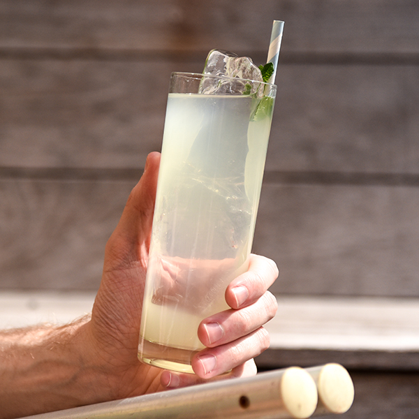 Person holding a glass of Analog Coconut Cooler cocktail 