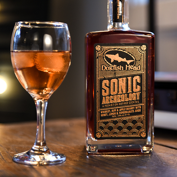 Sonic Archeology & Sauvignon Blanc cocktail Wine glass with mixed cocktail in it next to a bottle of Sonic Archeology