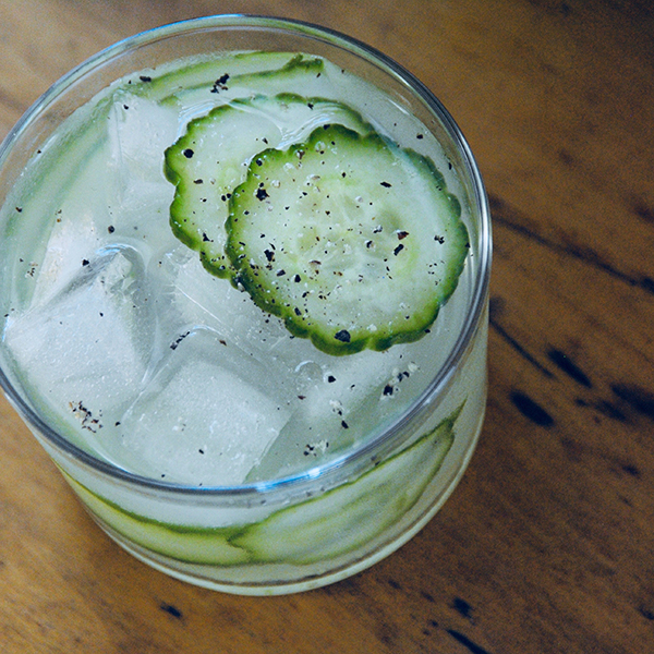 Above shot of a glass that has liquid and sliced cucumbers in it