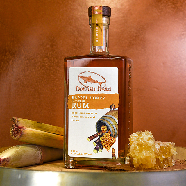 Bottle of Barrel Honey Rum surrounded by cinnamon sticks and honey combs 