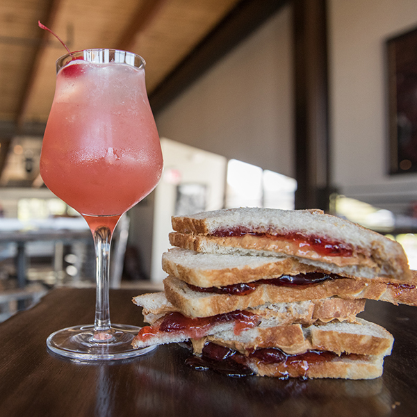 Cocktail glass filled with PB&J Punch with a plate filled with PB&J sandwiches on the right