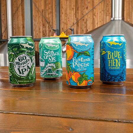 Cans of 60 Minute IPA, Blue Hen Pilsner, Festina Pêche and SeaQuench Ale sitting in Brewhouse 2 at Dogfish Head Milton