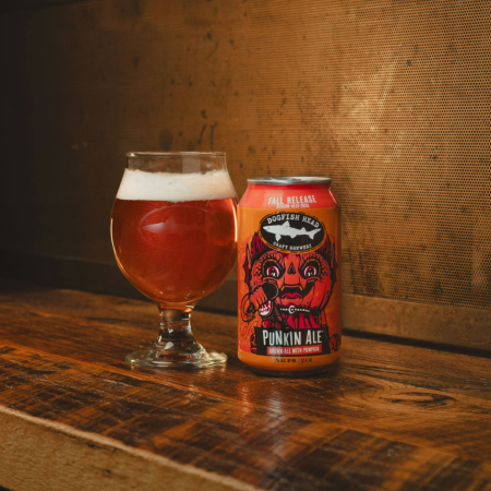 Dogfish Head Punkin Ale 12 oz can on a counter top with a glass of the beer next to it