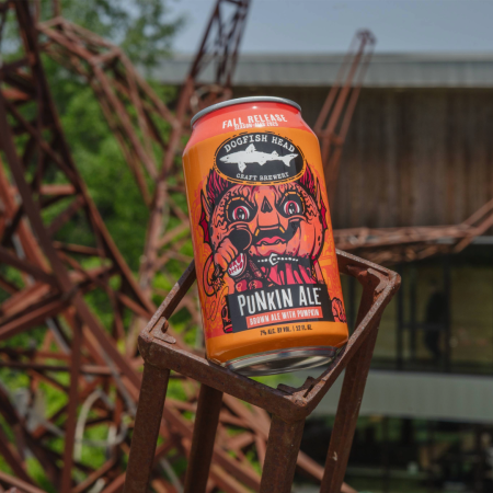 Dogfish Head Punkin Ale 12 oz can sitting on an industrial machine with a six-pack in the background