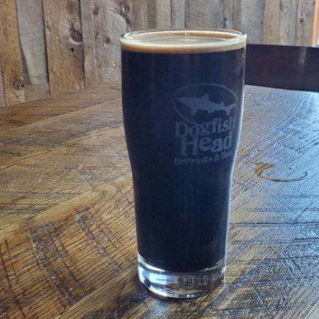 Dark beer in pint glass sitting on bar.