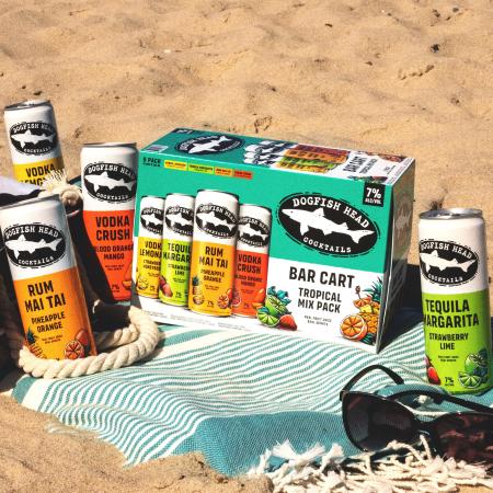 Tropical Bar Cart sitting on blanket on the beach with cans next to the 8-pack box