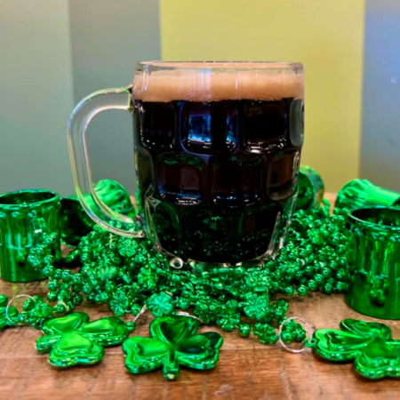 dark beer in a mug with green St. Patrick's Day beads around it