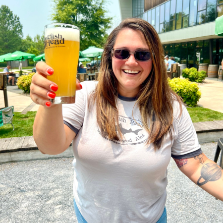 Dogfish coworker holding a pint of a hazy IPA outside the Milton Brewery 