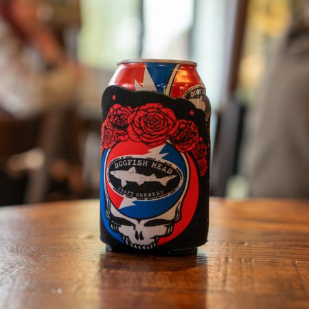 A black can cooler with the Dogfish Head and Grateful Dead collaboration skull logo on the front and red roses around the top.