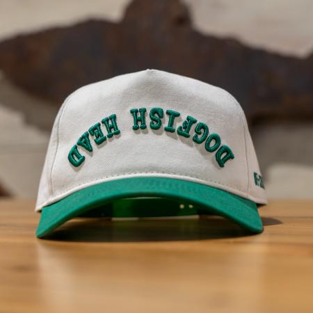 A cream colored five panel hat with a green brim and green embroidery that says "Dogfish Head" upside down.