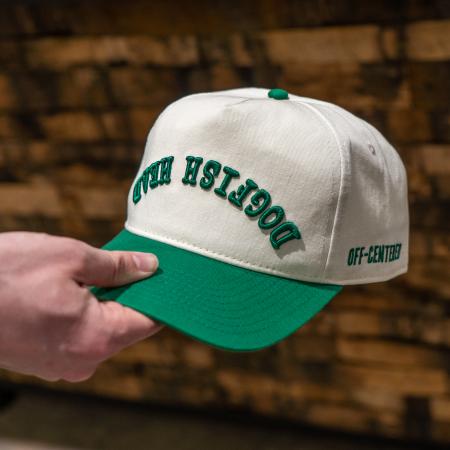 A cream colored five panel hat with a green brim and green embroidery that says "Dogfish Head" upside down.