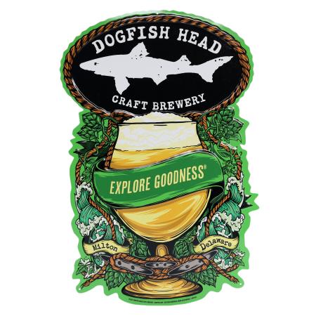 A colorful Dogfish Head tin tacker featuring a foamy beer goblet with a green “Explore Goodness®” banner, surrounded by hops, vines, and ocean waves. “Dogfish Head Craft Brewery” appears at the top, with “Milton, Delaware” written in scrolls at the bottom
