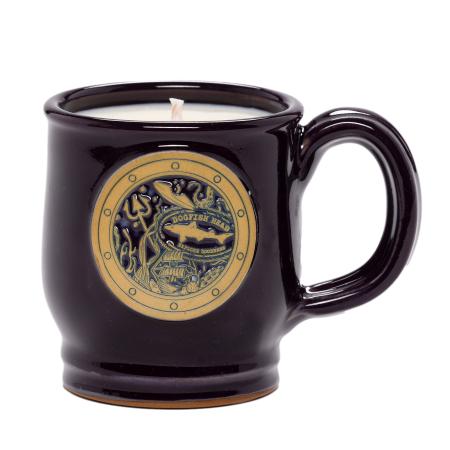 A rich plum ceramic Dogfish Head mug candle featuring a circular porthole-style emblem with ocean-themed details and the Dogfish Head shark logo on the front. 