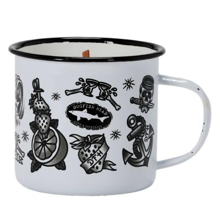 A white enamel mug candle featuring vintage-style black-and-white tattoo graphics, including anchors, mermaids, citrus, and Dogfish Head branding, with a wooden wick in the center.