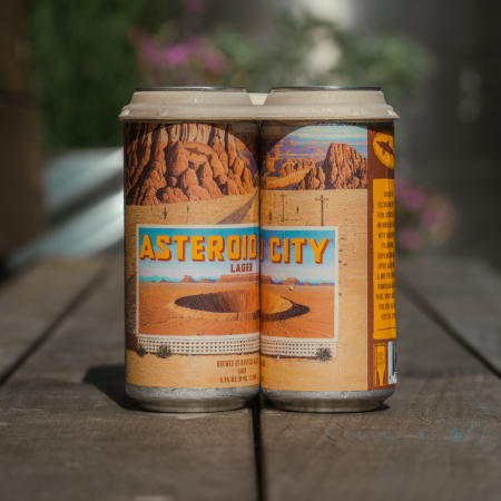 Four Asteroid City Lager cans sitting in grassy area