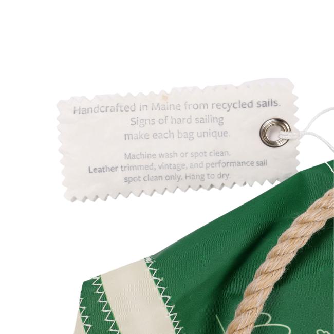 Close-up of the attached Sea Bags tag that reads: “Handcrafted in Maine from recycled sails. Signs of hard sailing make each bag unique.”