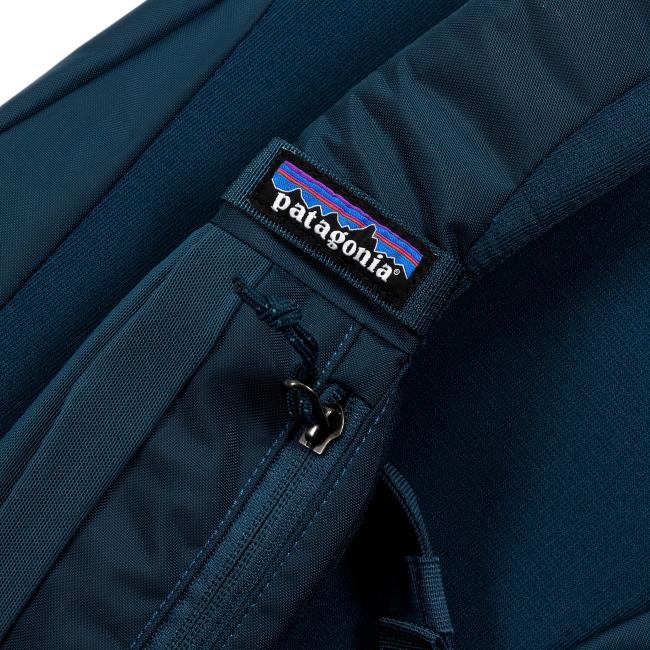 Detailed close-up of the back strap area showing the Patagonia logo tag stitched onto navy blue fabric with a visible zipper and reinforced seams.