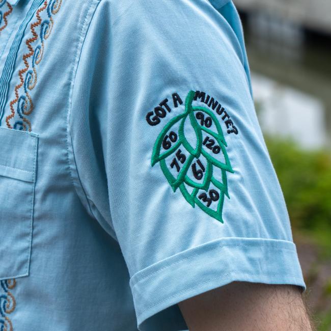 Close up of embroidered hop design with text Got a Minute and numbers of 60 minute series inside the hop