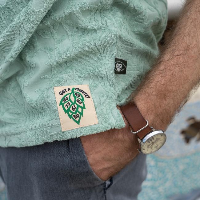 Male model wearing Howler short sleeve textured terry polo with Dogfish Head Since 95 embroidered logo. Close up of Dogfish Head designed Hop label  and Howler tag