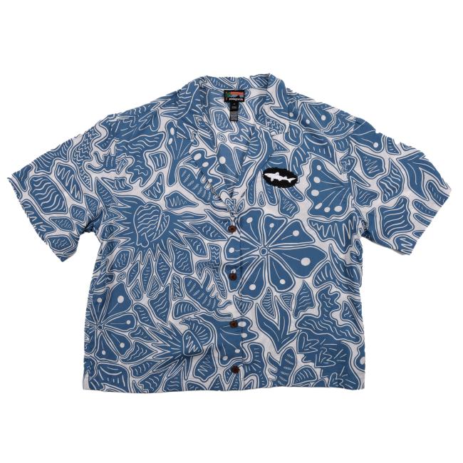 Front view of a short-sleeve Patagonia button-up shirt featuring an all-over blue and white abstract floral and leaf pattern, with a black and white Dogfish Head shark logo patch on the left chest.