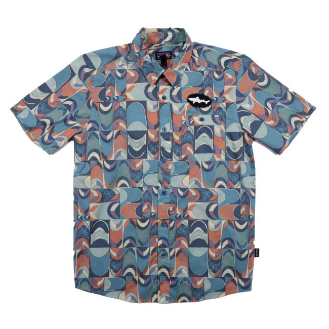 Front view of a short-sleeve Patagonia button-up shirt featuring a vibrant retro geometric print in shades of teal, coral, cream, and navy. The left chest is detailed with a black oval Dogfish Head shark logo patch.