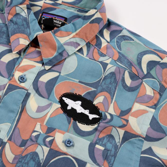 Close-up of the shirt’s collar area, highlighting the multicolor print, blue buttons, black Dogfish Head shark logo patch, and Patagonia brand tag inside the collar.