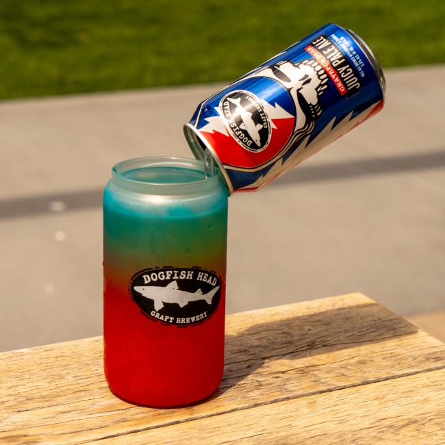 Image of a blue and red Dogfish Head can pouring into the ombre glass, activating the color change.
