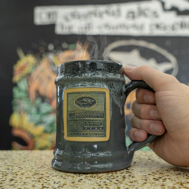 Dogfish Head Grey Analog Ceramic Mug With Analog Image Carved Into The Front With Model Holding The Mug