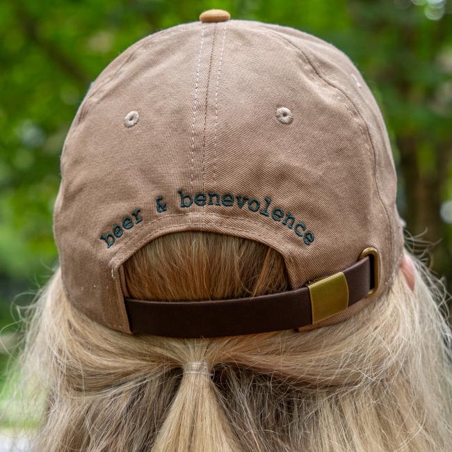 Back view of the hat showing “beer & benevolence” embroidered above the adjustable strap.