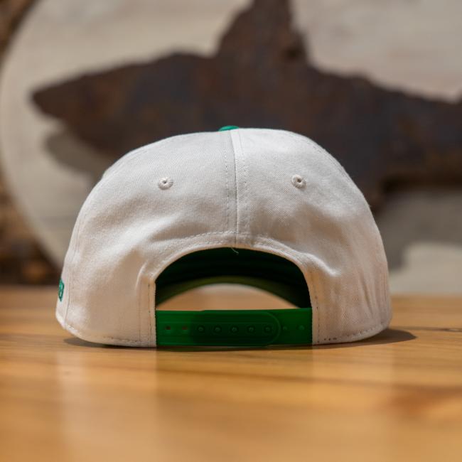A cream colored five panel hat with a green brim and green embroidery that says 