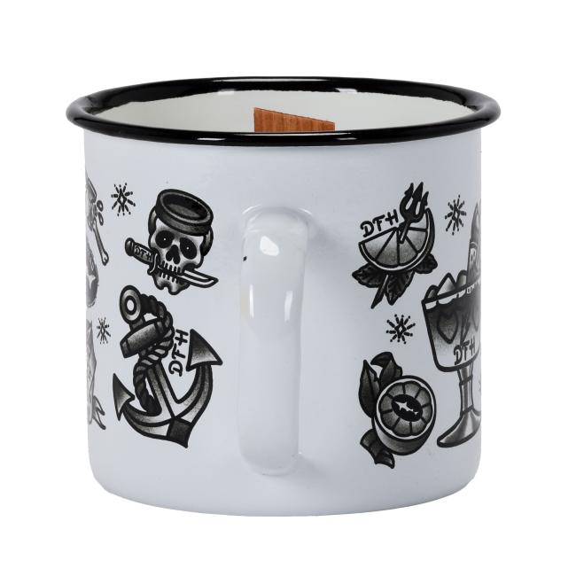 A white enamel mug candle featuring vintage-style black-and-white tattoo graphics, including anchors, mermaids, citrus, and Dogfish Head branding, with a wooden wick in the center.