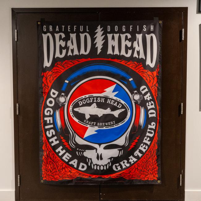 Dogfish Head x Grateful Dead rectangular flag featuring large scale print of skull and Dogfish logo. Colors include black, red, blue and white. 