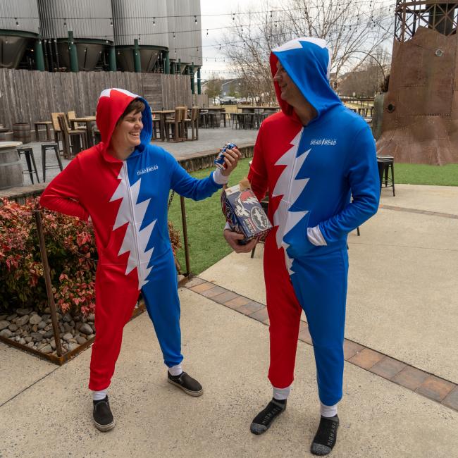 Adult unisex hooded zip front onesie. Red and blue with white grateful dead lightening bolt. Small Dogfish Head text. 