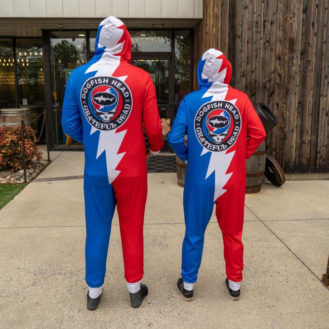 Adult hooded zip front onesie. Red and blue with white grateful dead lightening bolt. Circle logo with Grateful dead Skull and Dogfish Head shark logo.  