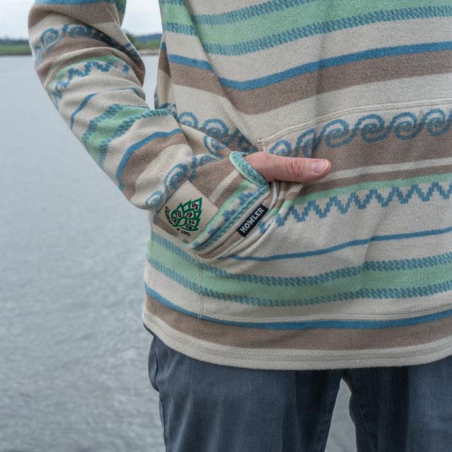 Male model wearing Howler collaboration multi stripe terry cloth stripe hoodie. Close up of kangaroo pocket front and thumbhole sleeve detail