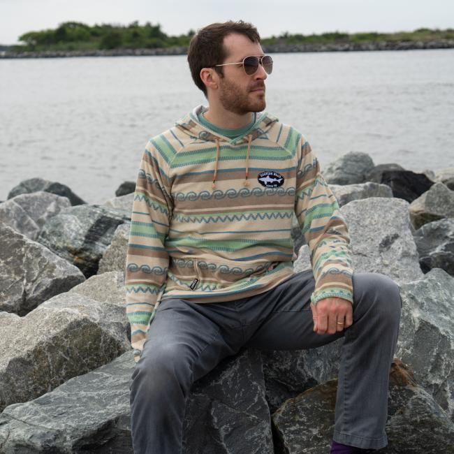 Male model wearing Howler multi stripe terry cloth stripe hoodie with small Dogfish Head shark & shield embroidered logo on left chest area. 