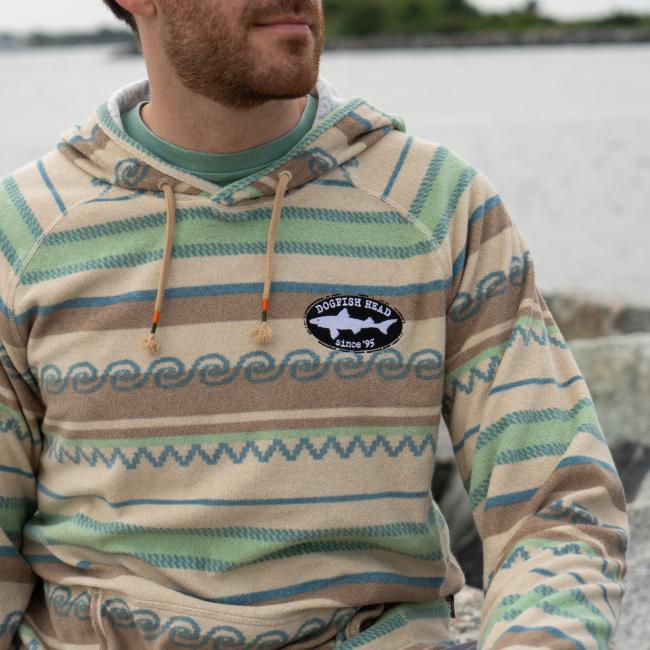 Male model wearing Howler multi stripe terry cloth stripe hoodie with small Dogfish Head shark & shield embroidered logo on left chest area. 