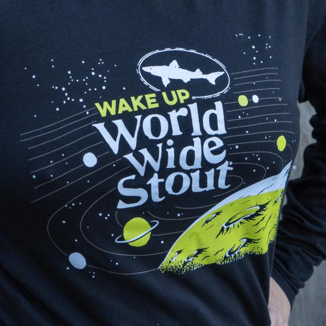 Dogfish Head World Wide Stout Long Sleeve Tee in Black With Glow In The Dark Galaxy And Planet On The Front In Green And White Up Close Image of Front
