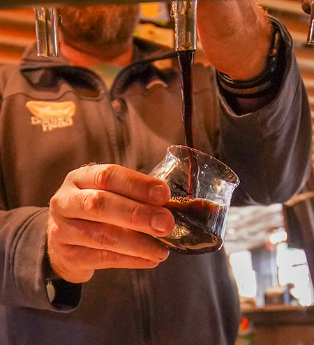 A short tulip shaped glass being filled with a hazy IPA during Dogfish Head Analog A Go Go
